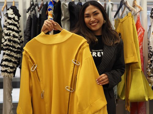 Fashion designer holding up her yellow sweater that she designed
